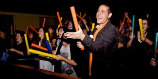 A group of people smile as they play colorful boom whackers.